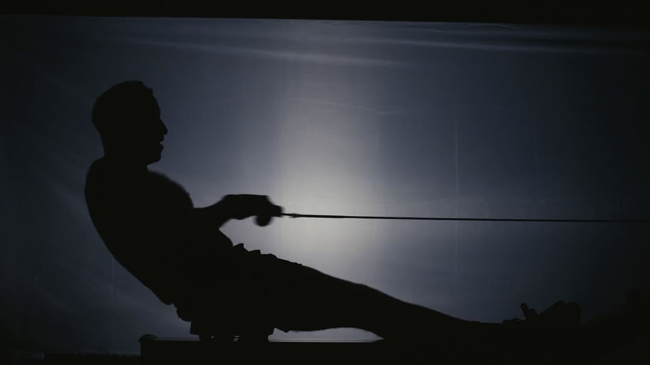 Silhouette of an athlete on a rowing machine under a single light